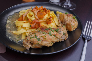 Tagliatelle with chanterelles and stewed rabbit on black terelke. side and top view. Italian pasta homemade food. setout