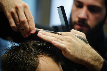 The Barber a man with a beard in the process of cutting the client a pair of scissors in the...