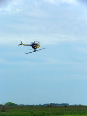 Model of a helicopter on the remote control flying upside down in blue sky