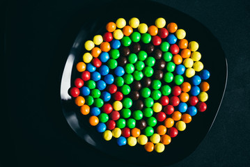 The question mark out of the candy skittles . Colorful jelly beans are on a black plate - 125526618