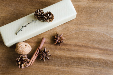 Vintage Christmas Kraft Gift Box in Rustic Style Decorated with Pine Cones on Wooden Background.