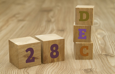 Cube shape calendar for December 28 on wooden surface.
