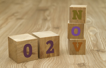 Cube shape calendar for November 02 on wooden surface.