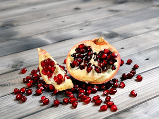 Closeup of ripe pomegranate fruit and seeds on an antique wooden base