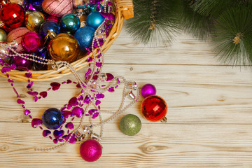 Jewellery chains and balls for the Christmas tree lying in a wicker basket close branches of spruce...