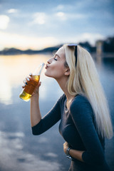 Young woman kissing beer bottle 