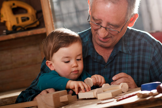 Senior carpenter and his grandson having fun in the workshop
