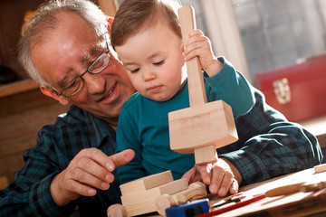 Senior carpenter and his grandson having fun in the workshop