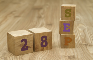Cube shape calendar for September 28 on wooden surface.