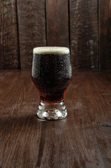 Glass beer on dark wood background. Dark beer