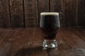 Beer glass with drops on dark wood table