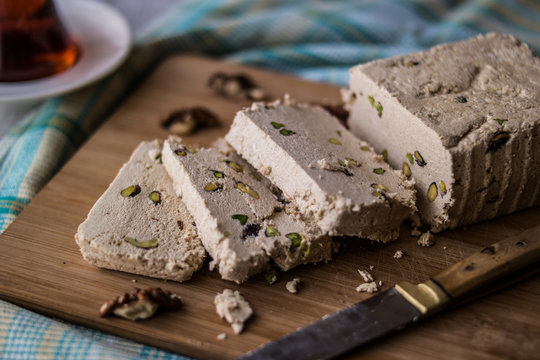 Slices of Halva with Peanut, walnut and tea on a wooden surface.