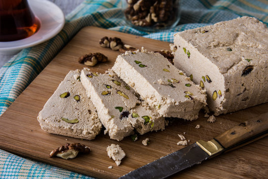 Slices of Halva with Peanut, walnut and tea on a wooden surface.
