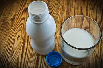 A small bottle of milk and poured a glass of milk on wooden back