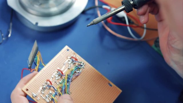 close-up shot of an electronics engineer developing and soldering a electronic circuit on a perfboard
