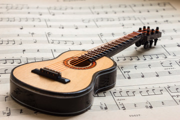 Little Acoustic guitar laying sheet music closeup