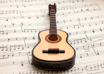 Fototapeta na wymiar Little Acoustic guitar laying sheet music closeup