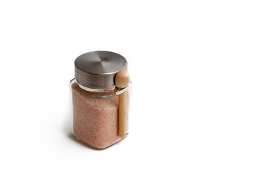 Pink salt are in a glass jar. Spice for cooking food on a white background.