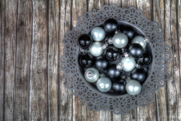 Dekoschale mit weißen und schwarzen Christbaumkugeln auf braunem Holzmuster