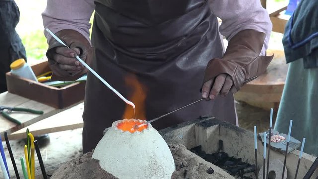 Reenactment of ancient times. Process of making glass beads on the fire. Manufacturer of jewelry