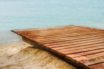 Wooden path on sand beach, sea in the background.