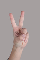 Human hand showing two fingers on grey background