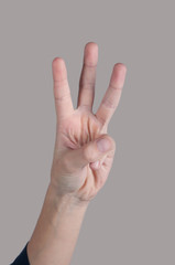 Human hand showing three fingers on grey background
