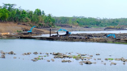 Fototapeta premium Three blue excavator working in construction site in big river