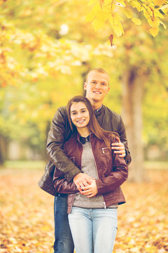 Young couple having fun in a park on one beautiful Autumn day.