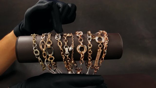 Jewelry in the store, Sold in black gloves shows gold jewelry in the store, a lot of gold bracelets, chains hanging on the exhibition stand in the jewelry store, the seller shows jewels