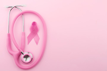 Obraz na płótnie Canvas Stethoscope with pink ribbon on color background. Breast cancer concept