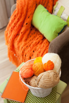 The boy hid under an orange knitted blanket. Brown background. 