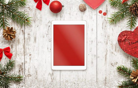 Tablet with isolated screen for mockup with christmas decorations on table. Top view of white wooden desk with christmas tree and gifts.