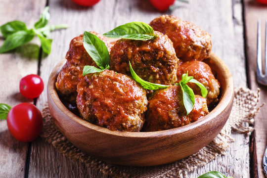 Meatballs with tomato sauce and basil, vintage wooden background