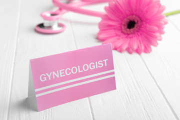 Business card with word GYNECOLOGIST on white wooden background, closeup