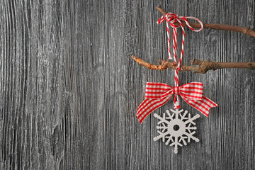 Christmas decor hanging on branch against grey wooden background