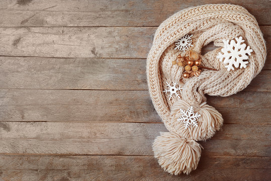 Knitted scarf and Christmas decor on wooden background