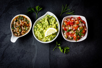 Traditional Latin American sauces Guacamole, Salsa, chili Pebre, slate background