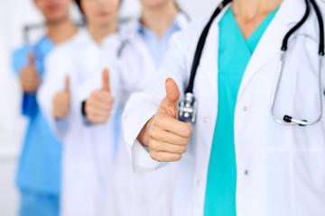 Group of doctors showing OK or approval sign with thumb up. High level and quality medical service, best treatment and patient care concept