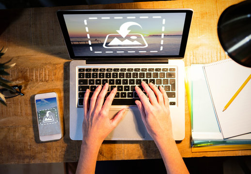 User with Laptop and Smartphone on Rustic Desk Mockup