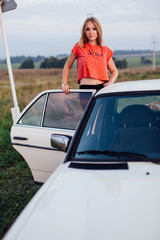 Portrait of a beautiful young woman standing near retro car