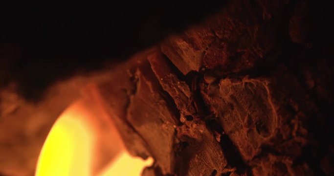 Dancing flame on burning logs. Glowing embers are burning orange and red. Winter warmth background. Filmed in slow motion.