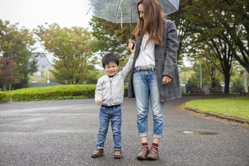 Fototapeta na wymiar Mother and son have a walk in the park holding an umbrella
