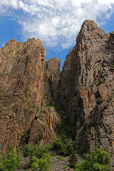 Fototapeta na wymiar Rock walls tower high overhead, seen from the floor of the Black Canyon of the Gunnison in Colorado.