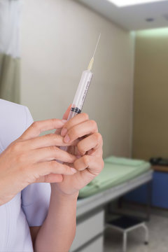 Hand of doctor  holding hypodermic syringe on hospital background.
