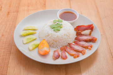 Barbecued red pork in sauce with rice on wood background. Thai f
