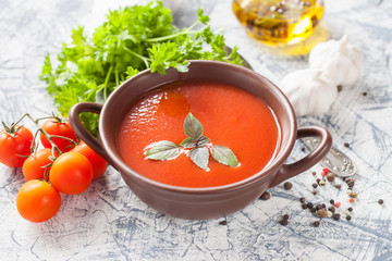 tomato soup with a basil in a bowl on a table, selective focus