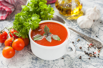 tomato soup with a basil in a bowl on a table, selective focus