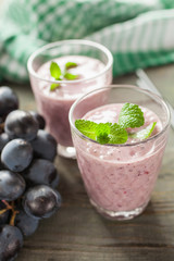 milkshake with banana and grapes in a glass on a table, selective focus