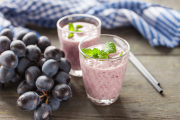 milkshake with banana and grapes in a glass on a table, selective focus